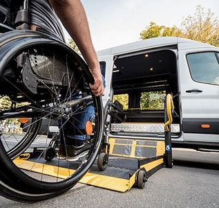 A man in a wheelchair is getting out of a van.