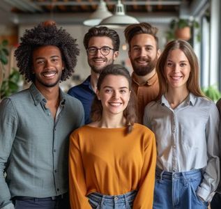 A diverse group of five smiling colleagues posing together in a brightly lit office setting.