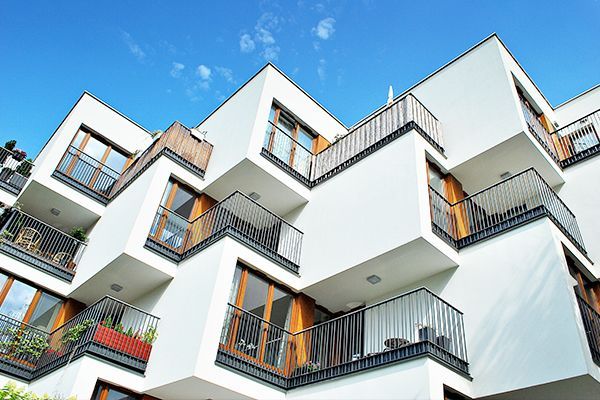 A large white apartment building with balconies and stairs.