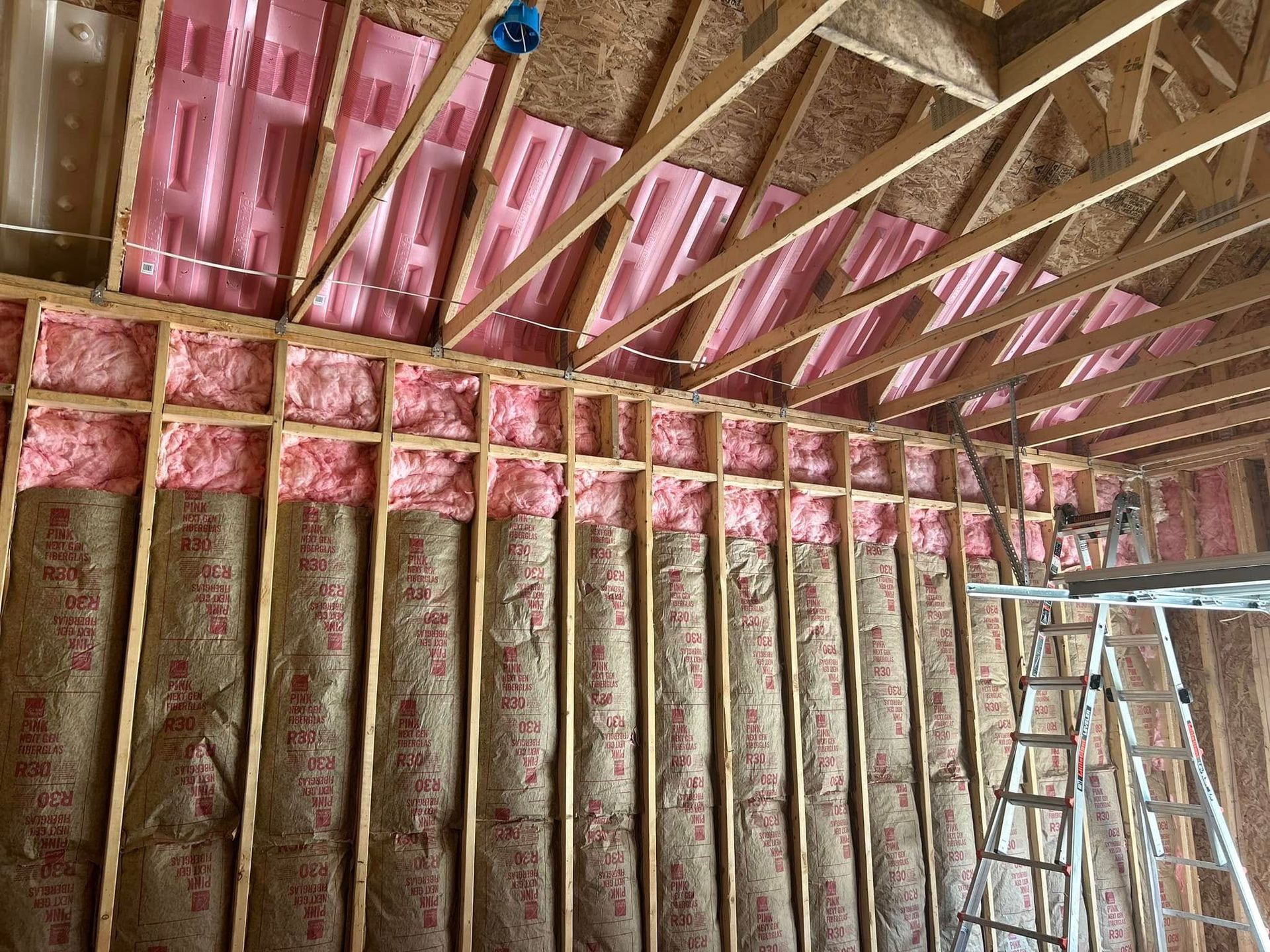 Interior view of a building under construction, showing a window, dark beam, wood joists, and concrete column.