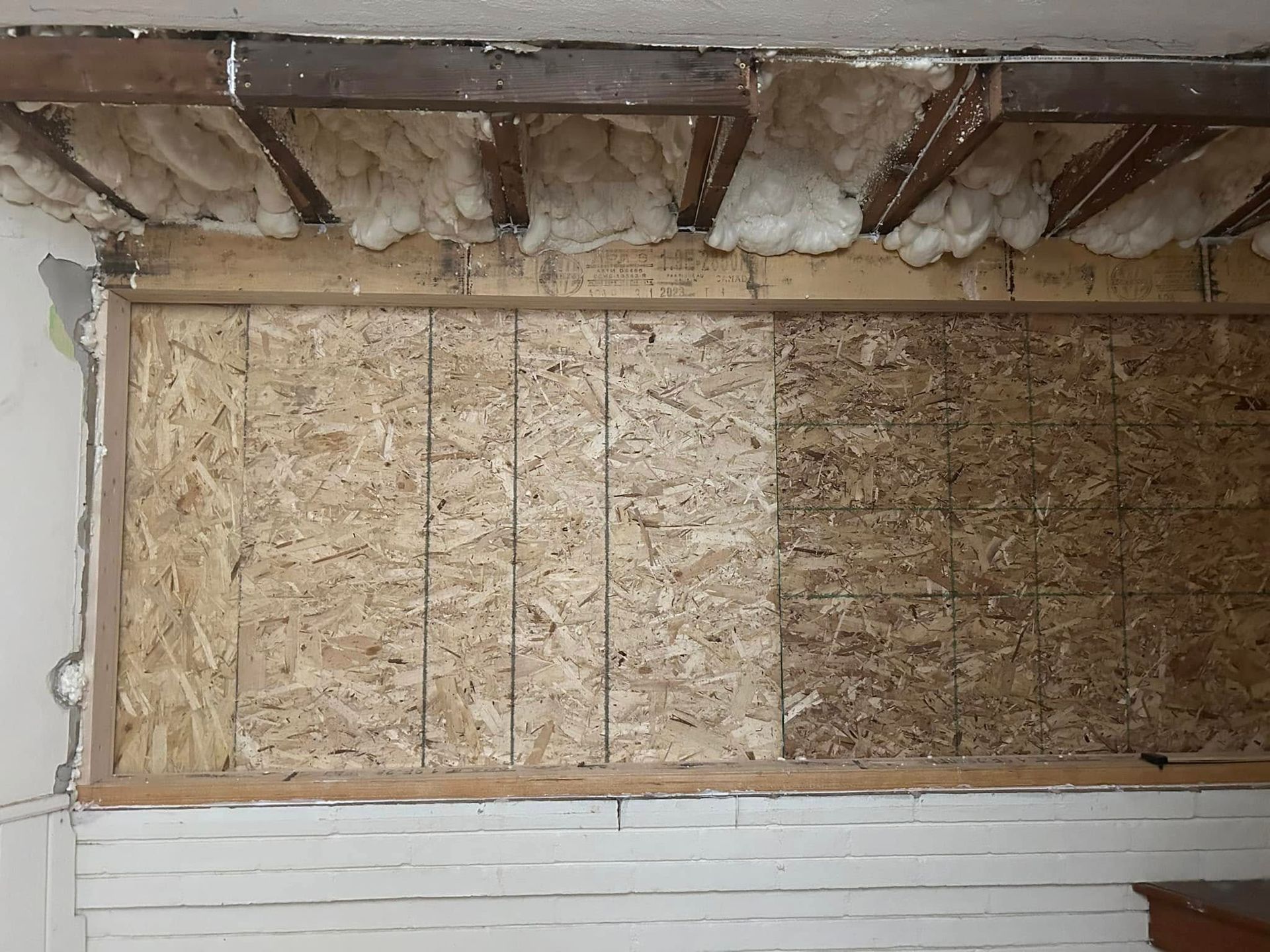 Wall section with exposed OSB paneling and insulation, potentially under repair.