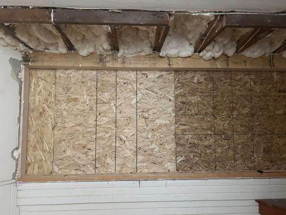 Wall section with exposed OSB paneling and insulation, potentially under repair.