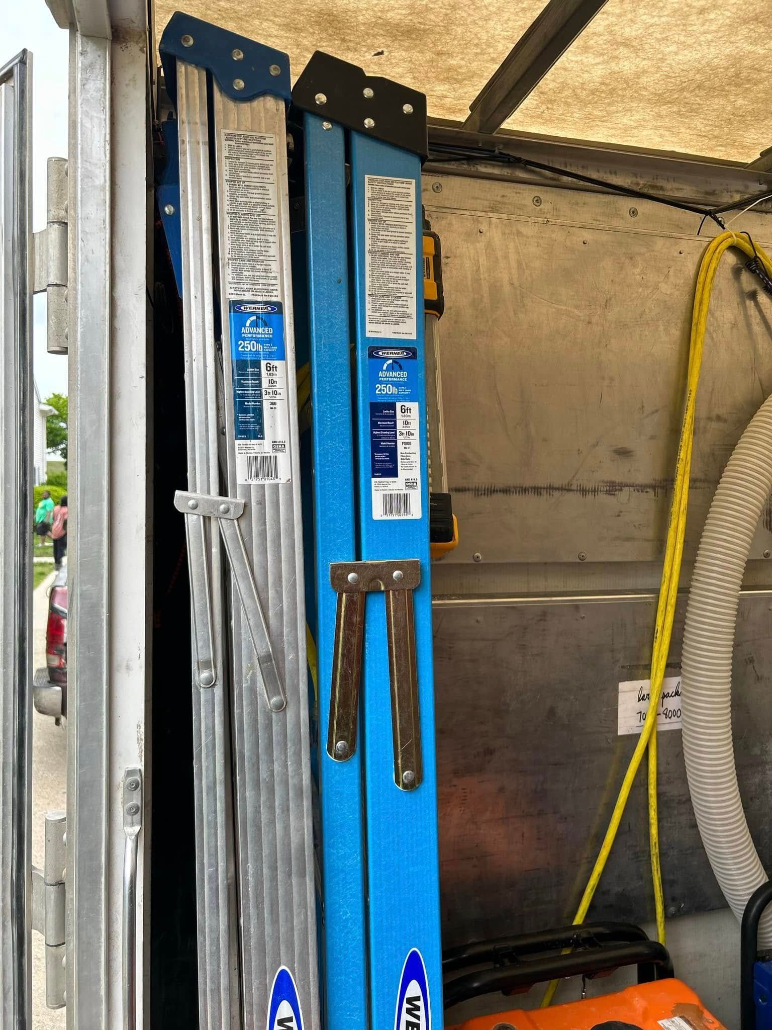 Two blue and silver Werner extension ladders inside a vehicle.