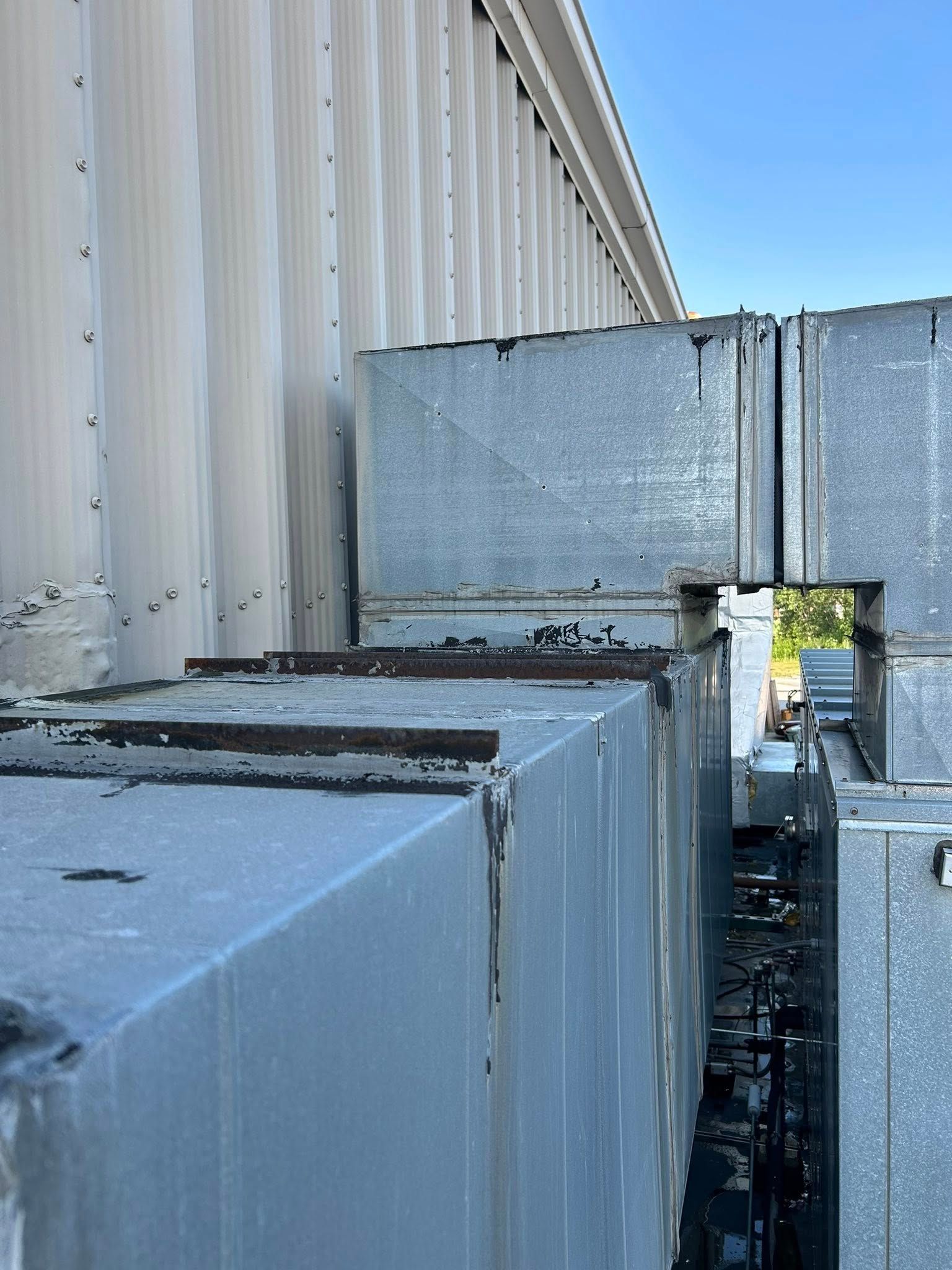 Metal HVAC ductwork on the side of a building, under a blue sky.