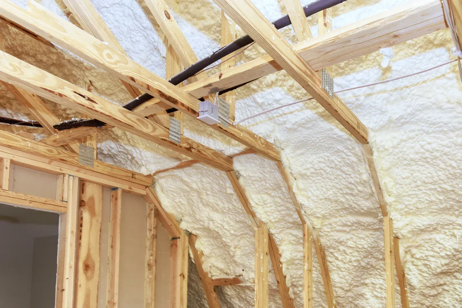 Wooden rafters and walls covered in light yellow spray foam insulation.