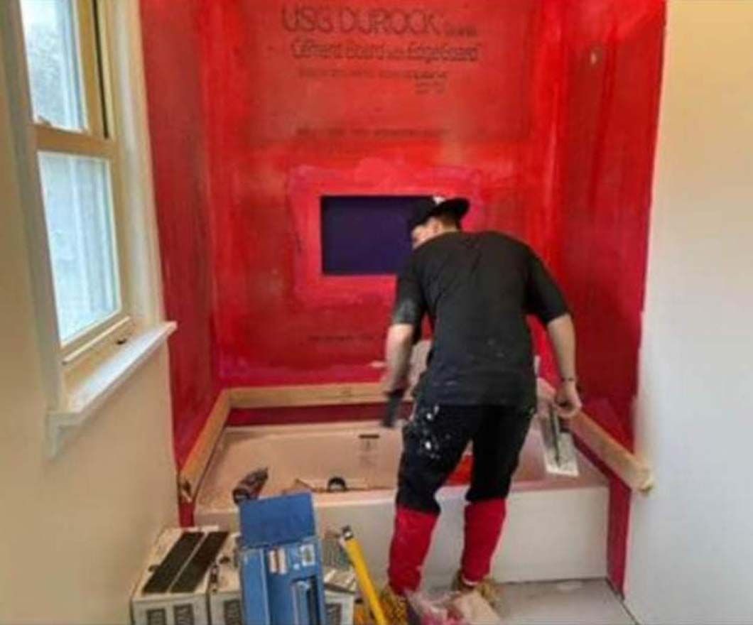 A man is working on a bathtub in a bathroom.
