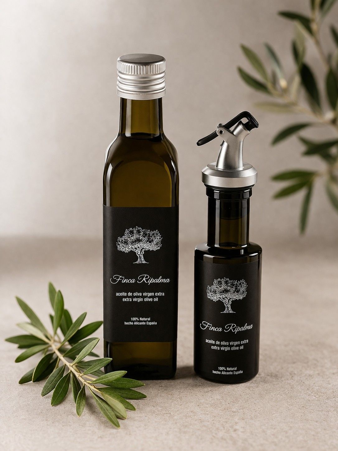 Twee donkere glazen olijfolieflessen met zwarte etiketten en een takje olijfbladeren op een lichte, neutrale achtergrond.