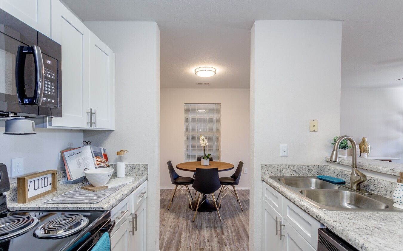 Kitchen and dining area with white cabinets, granite countertops, and a round dining table.