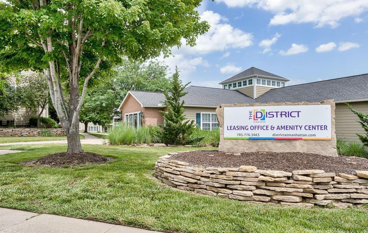 Sign for "District" leasing office and amenities center in front of a building.