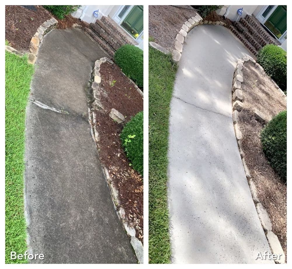 Before and after of a walkway, cleaned with a pressure washer. Dark, dirty cement to clean light gray. Green grass and plants surround.