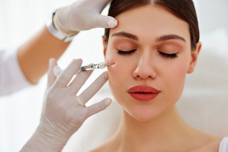 Cosmetician applying filler injection to patient