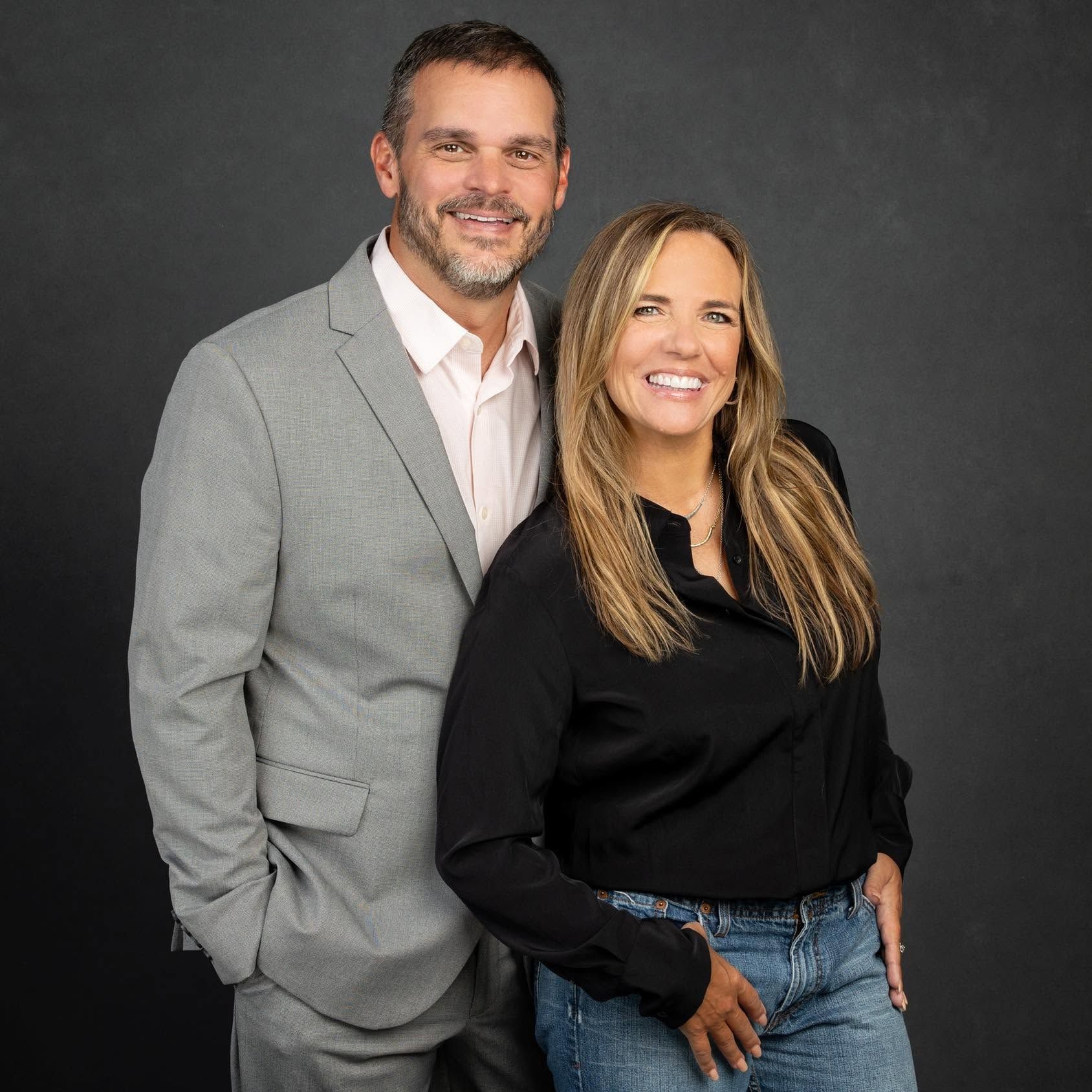 A man in a suit and a woman in a black shirt are posing for a picture.