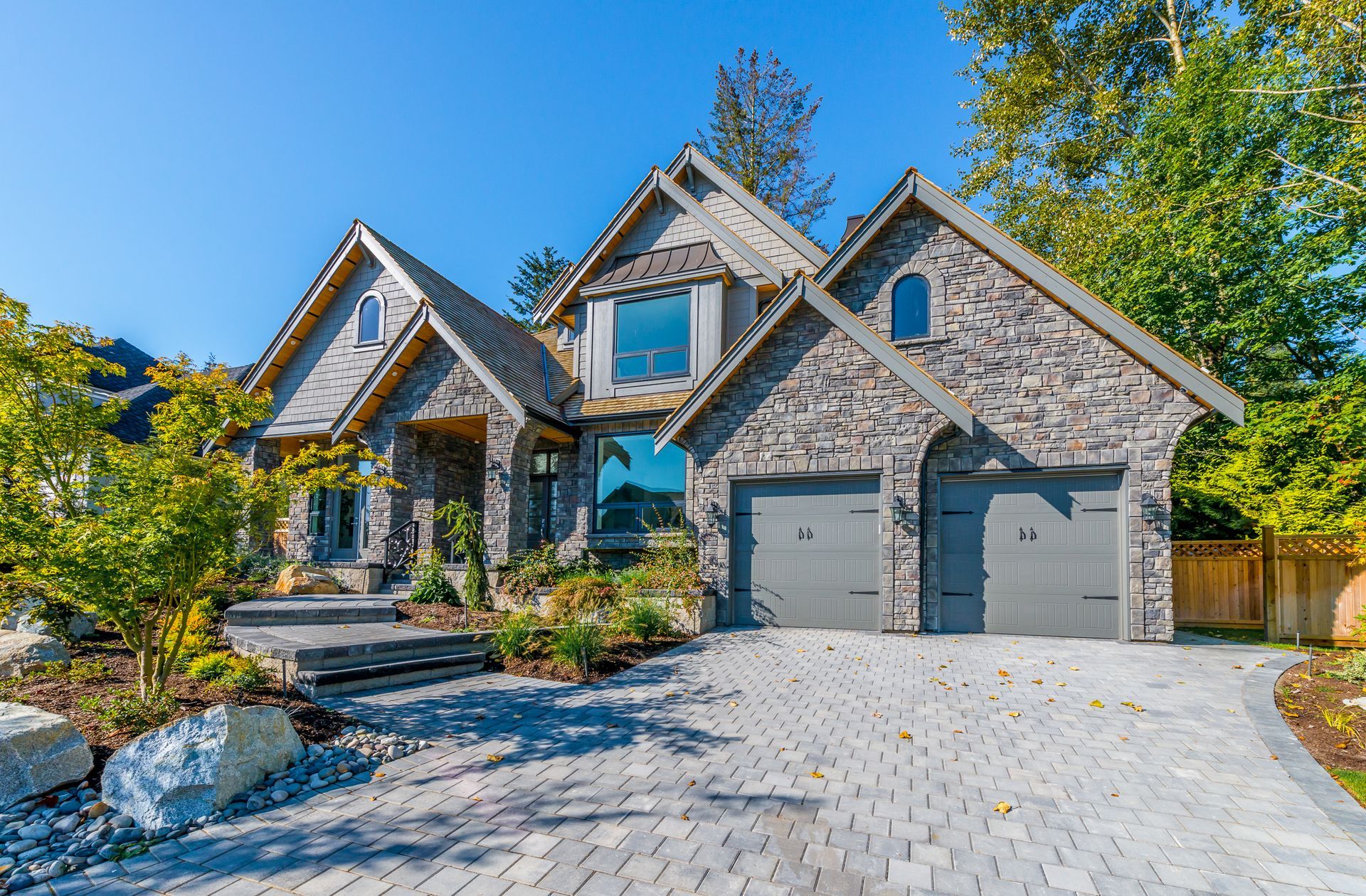 A large stone house with two garages and a driveway.