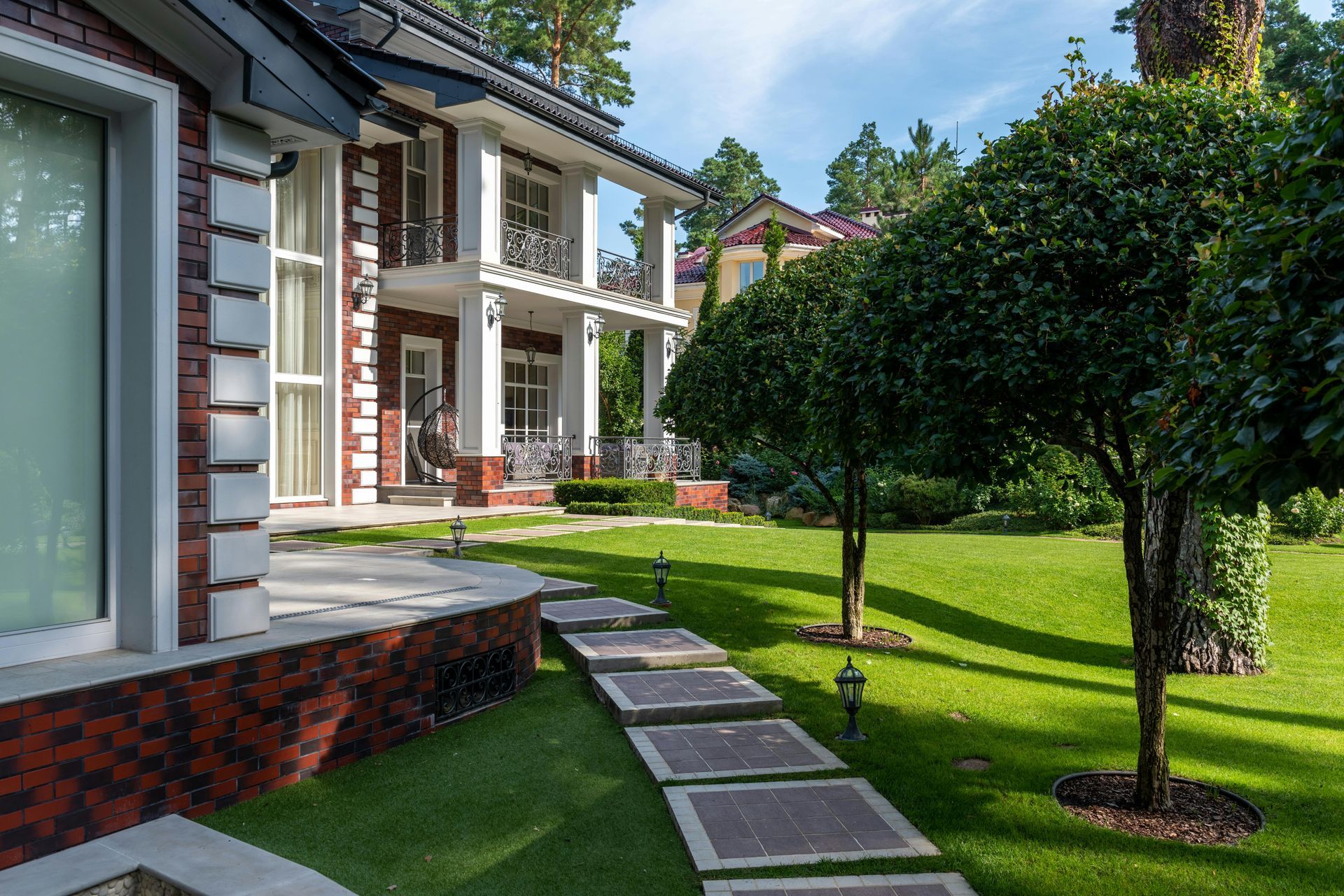 Modern house exterior with a manicured lawn, stepping stones, and trimmed trees