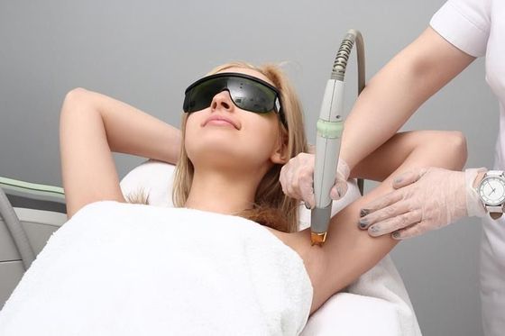 A woman is getting a laser hair removal treatment on her armpit.