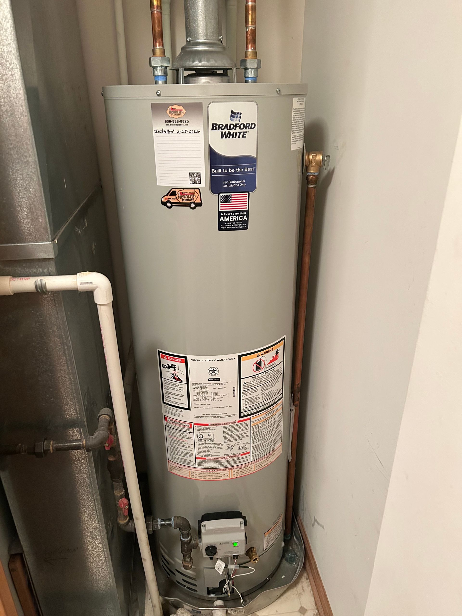 Plumber fixing pipes near a white water heater, indoors.