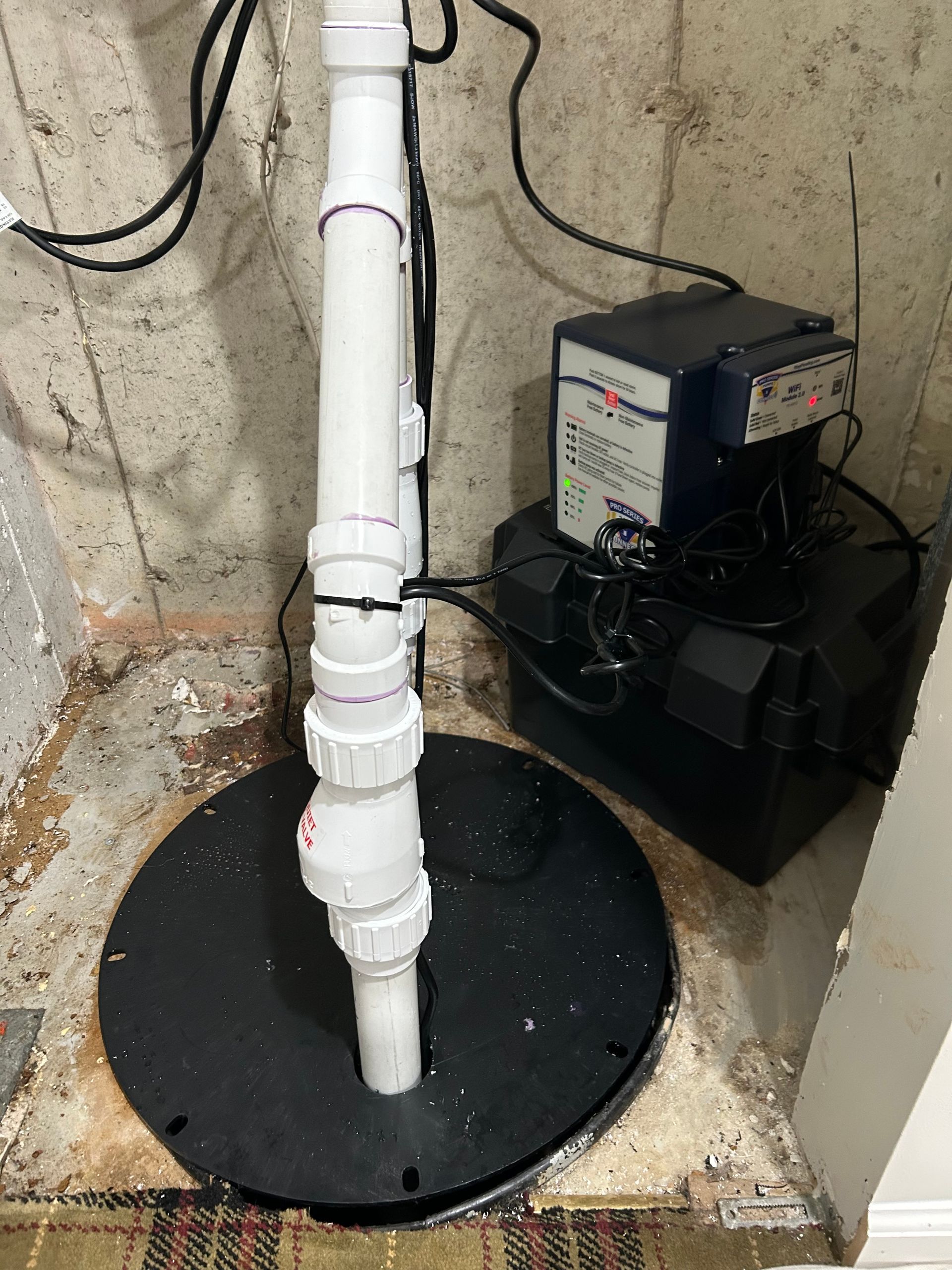 Overhead view of a concrete well with black tubing, wires, and a green valve.