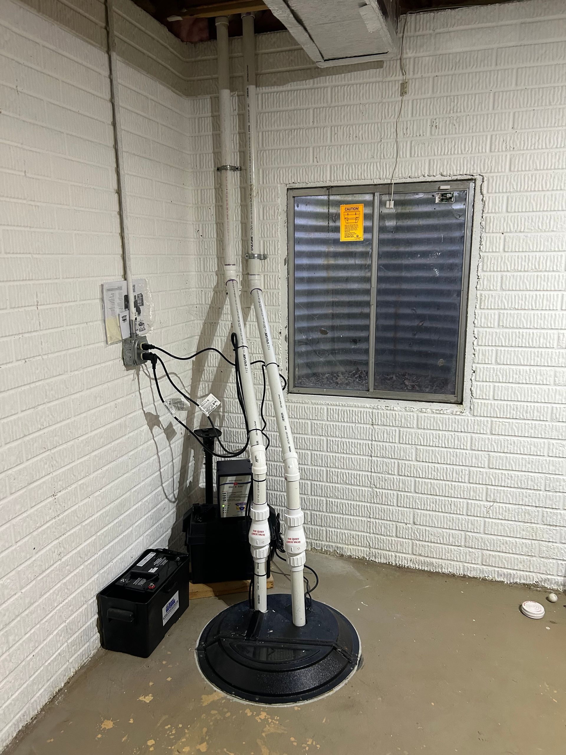 Person working on a septic tank. They are wearing sandals, hands holding a pump in the open tank.