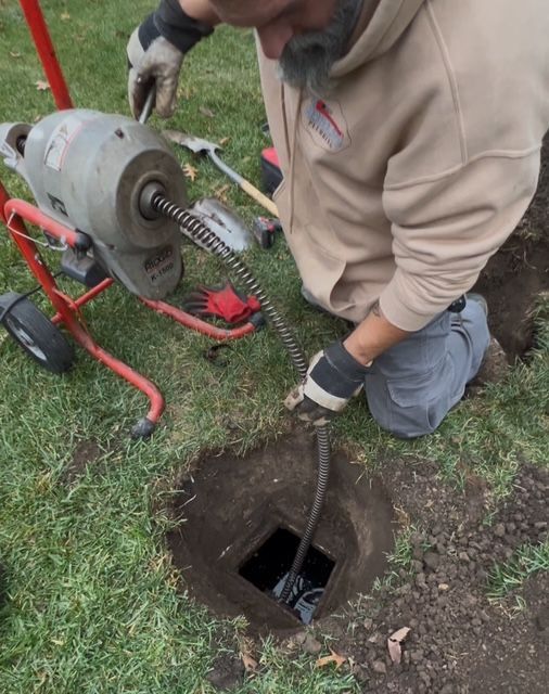 Person in blue work clothes inspecting a sewer with a camera.