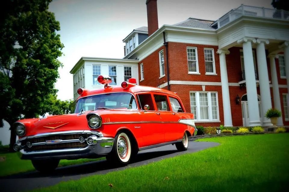 Old red hearse in front of Exterior view of McReynolds-Nave & Larson Funeral Home in Clarksville, TN.