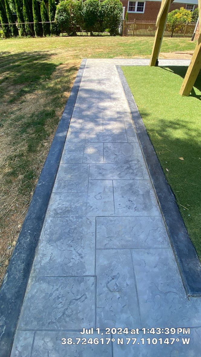 Concrete garden path between grass lawns leading toward a house in a sunny yard