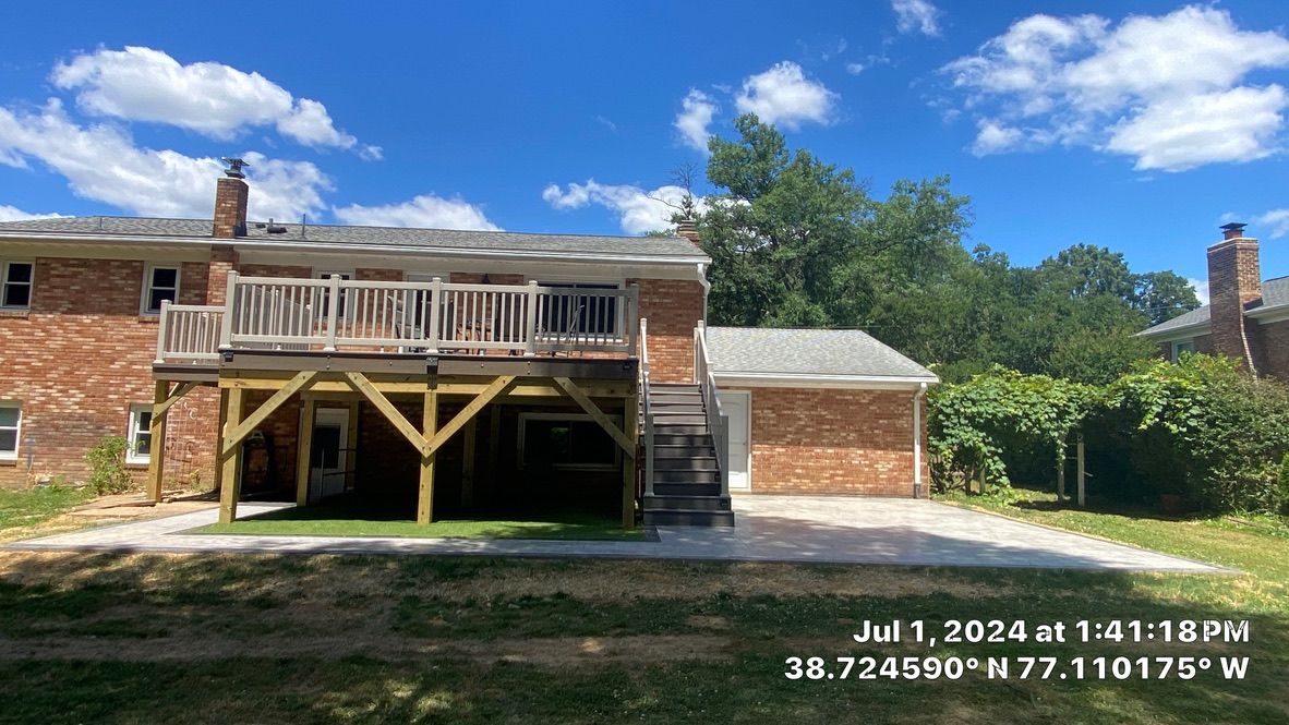 Brick house with wooden balcony and covered carport under a blue sky, with date and GPS text overlay.