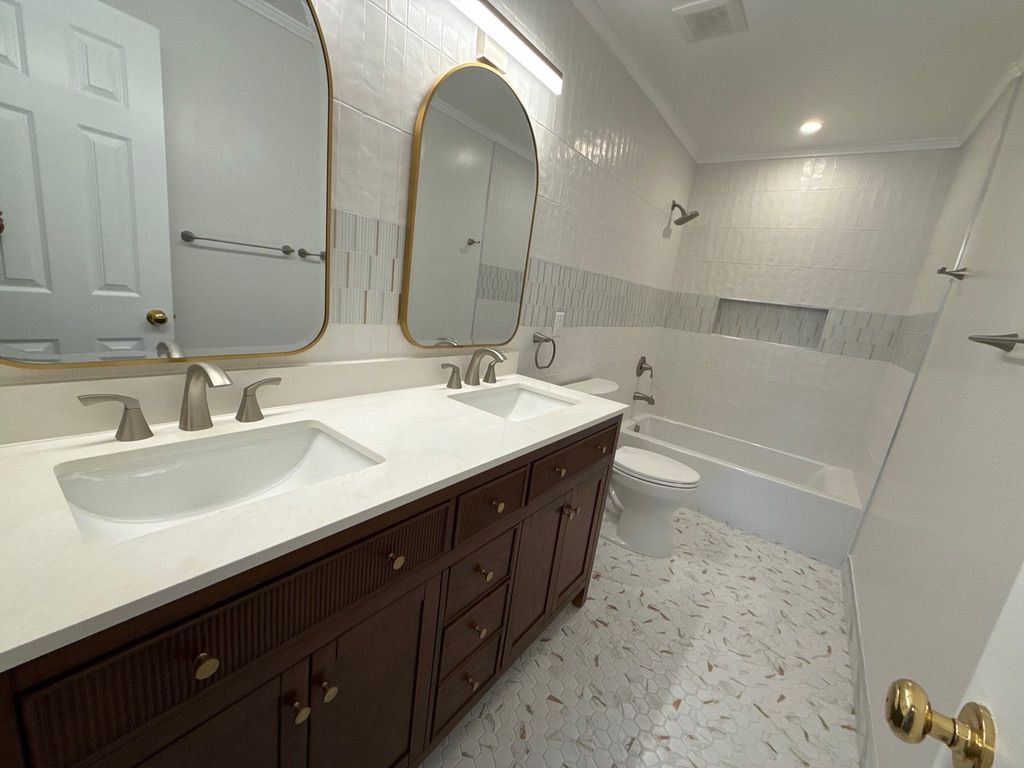 Spacious bathroom with double vanity, large mirrors, and a white tiled shower-tub area.