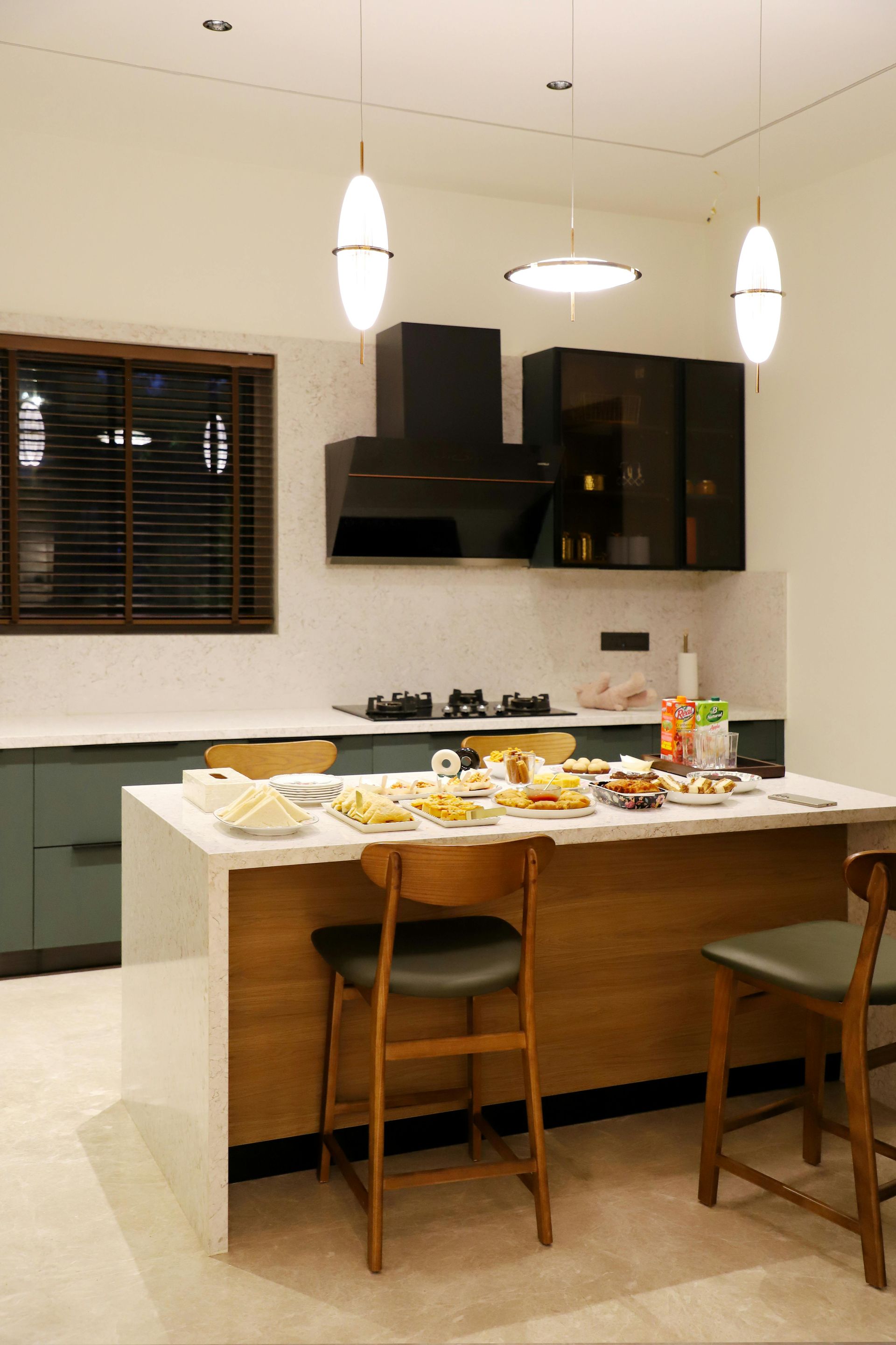 Modern kitchen with island, bar stools, pendant lights, and fruit on the counter.