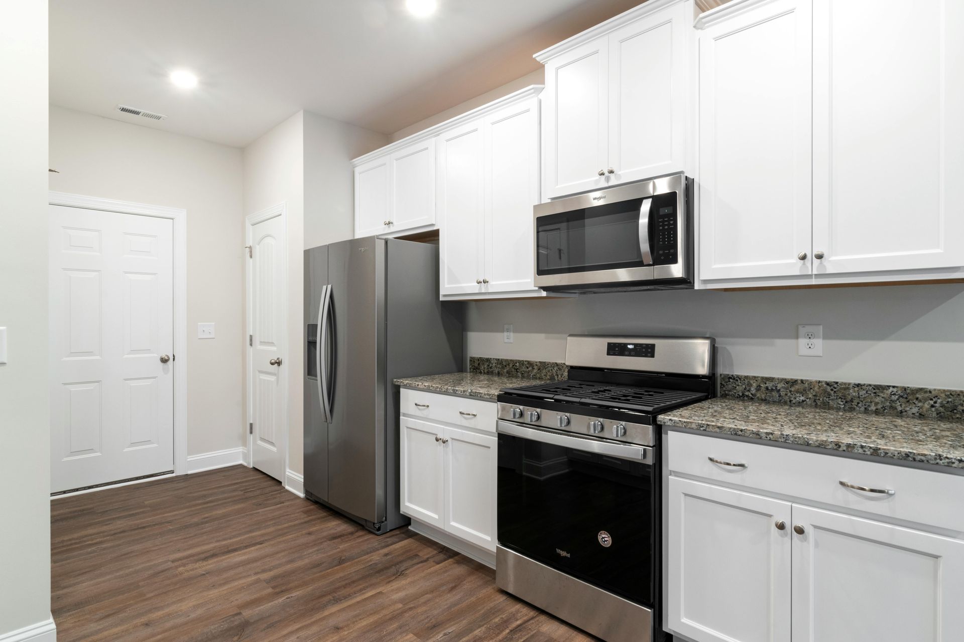 Modern kitchen with white cabinets, stainless steel appliances, and granite countertops.