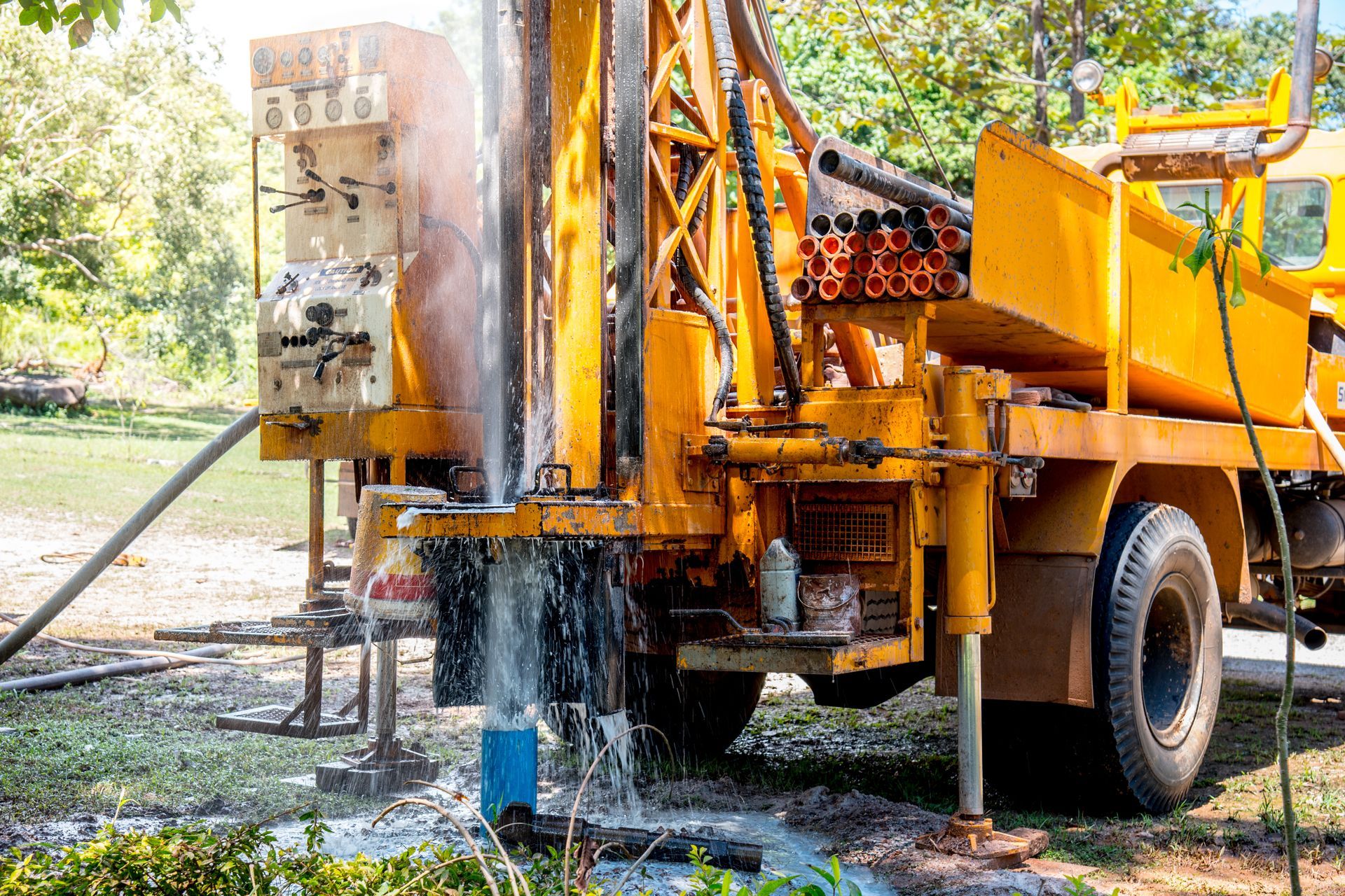 Water well drilling rig spraying water as the drill penetrates the ground on a work site