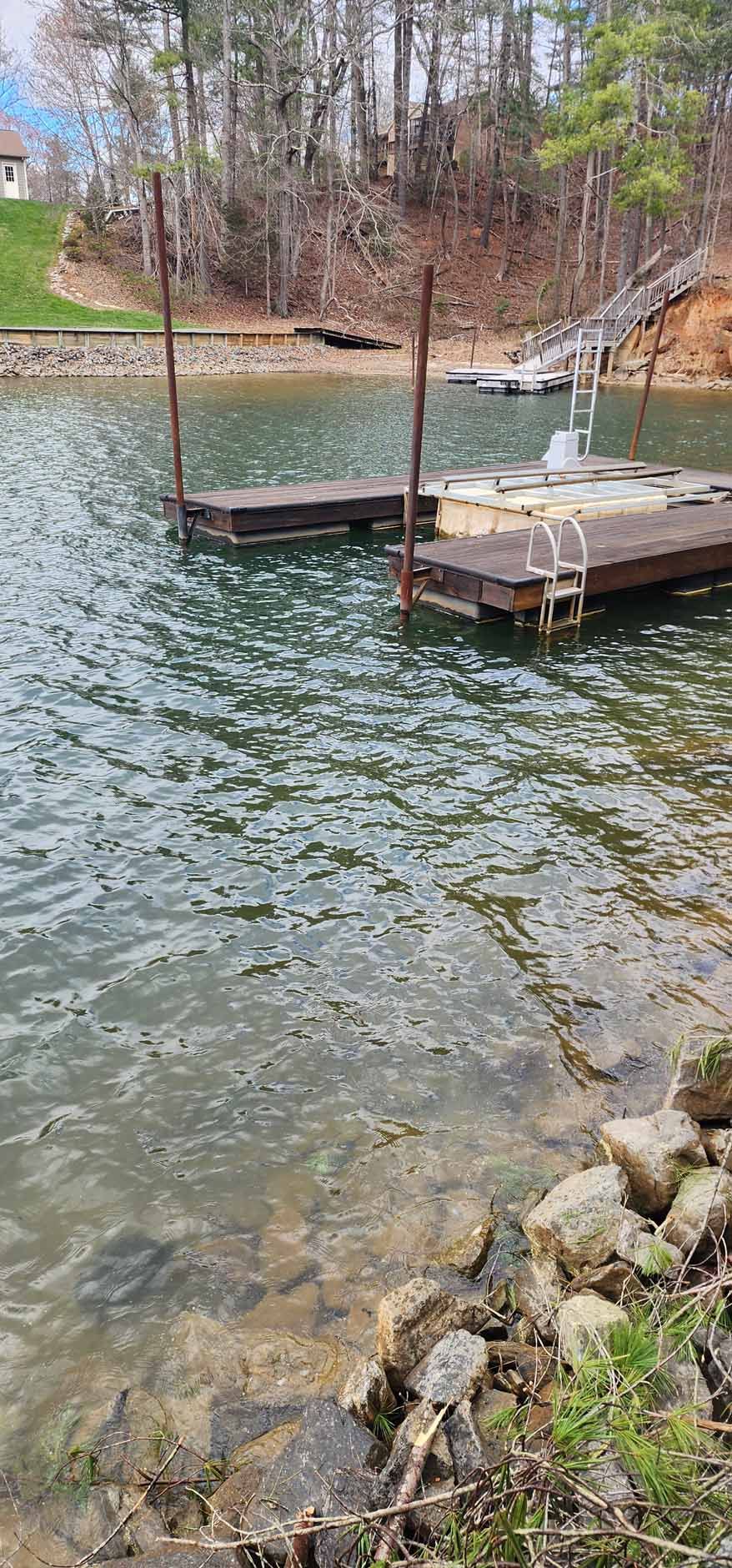 A dock with two platforms on a lake, with forest and rocks in the background.