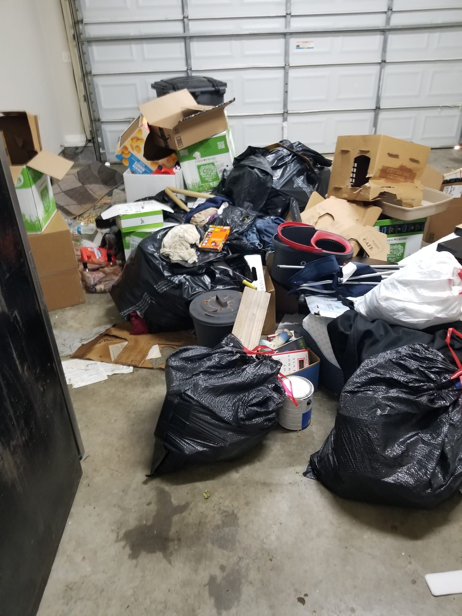 A garage filled with lots of boxes and trash bags.