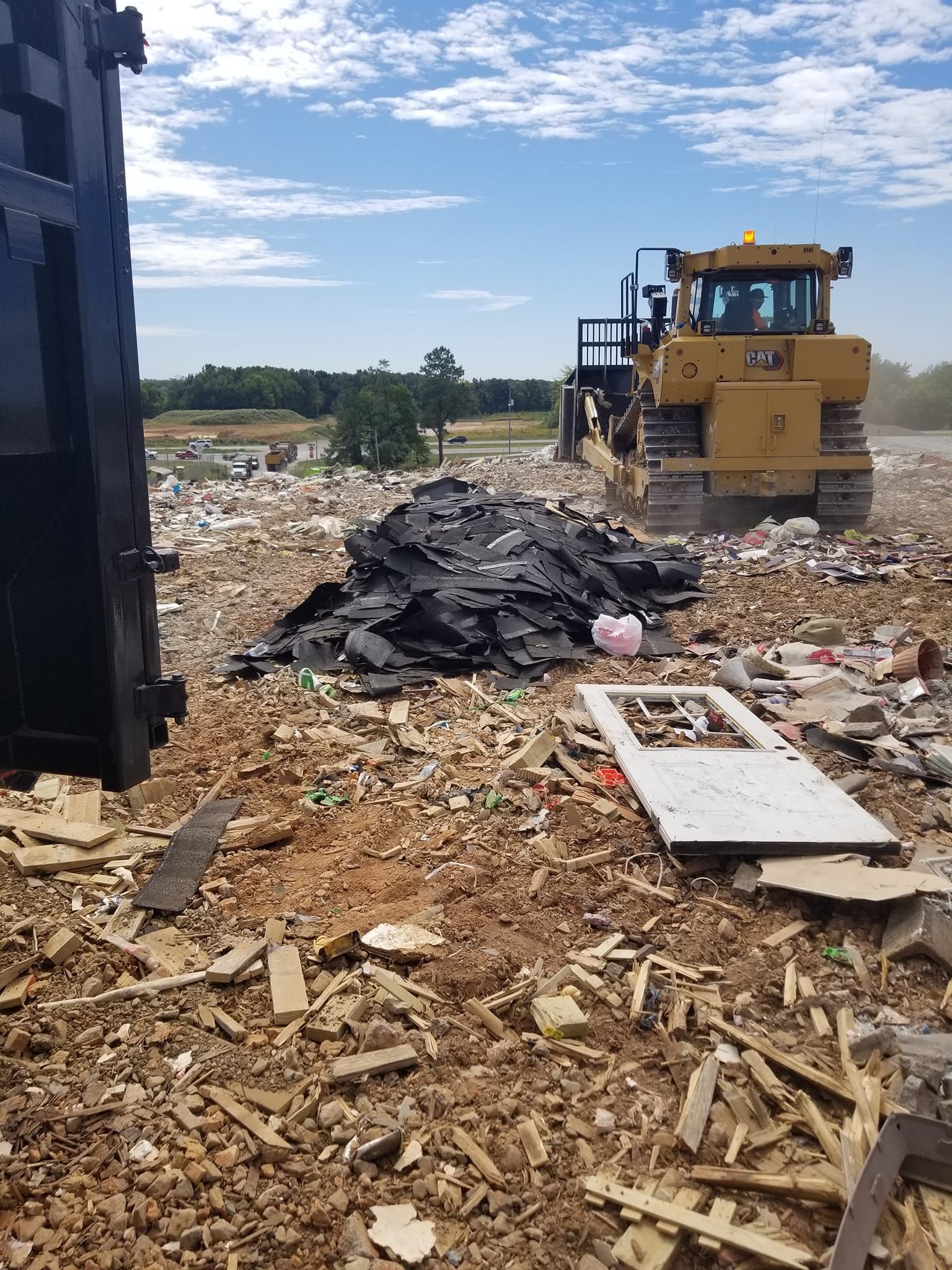 A bulldozer is moving a pile of trash in a dumpster.