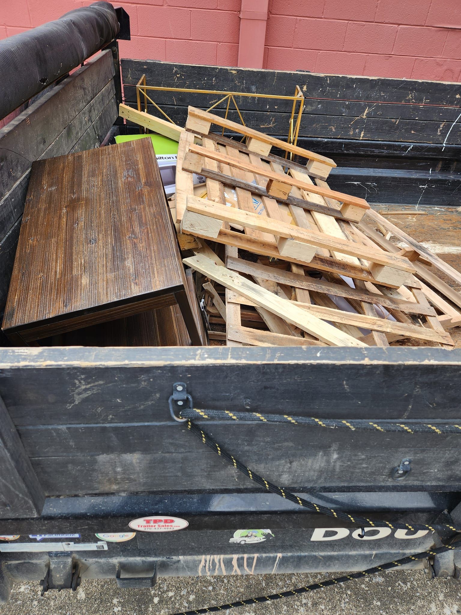 A truck bed filled with a wood pallet, a wooden object, and other debris.