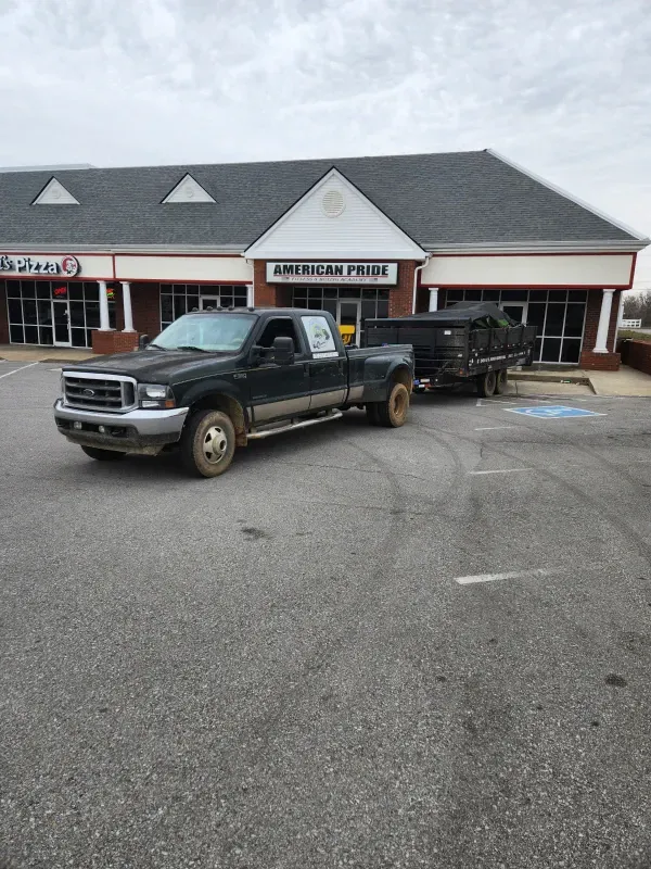 Dark truck towing a trailer in front of a store with the sign 