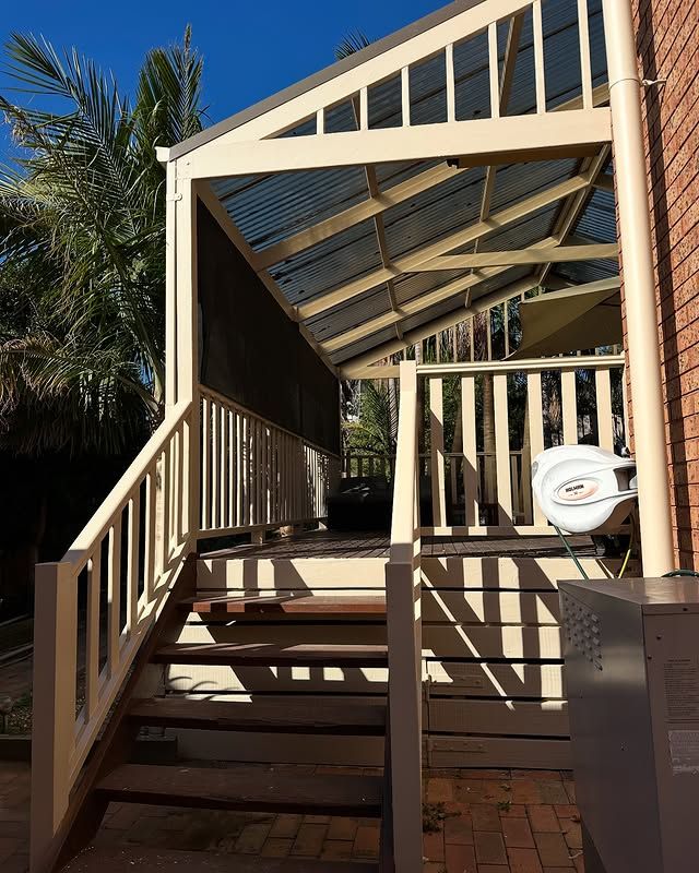 Interior room with three tall windows, a stepladder, electrical supplies, and a sander on the concrete floor. The walls are white.