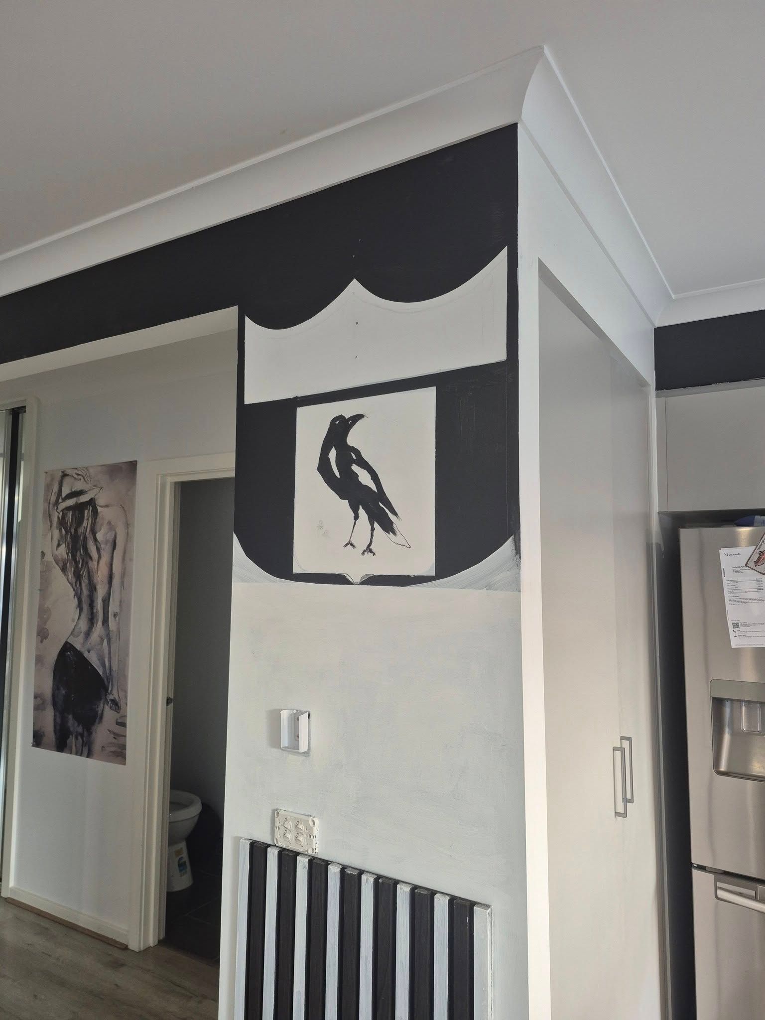 Black and white painted wall featuring a heraldic shield with a crow, along with a black border along the top.