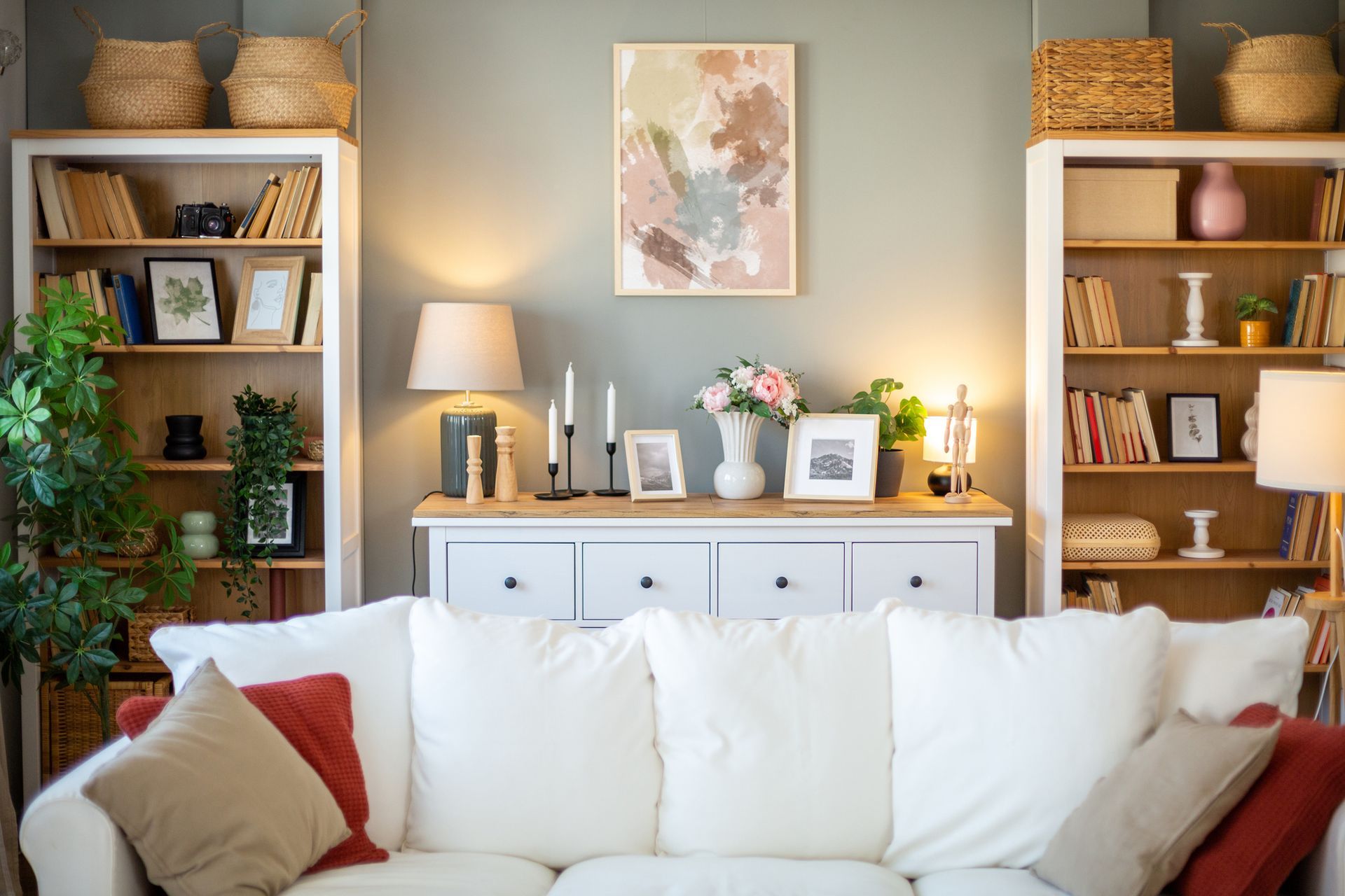 Living room with white sofa, bookshelves, and decorative items against a light green wall.