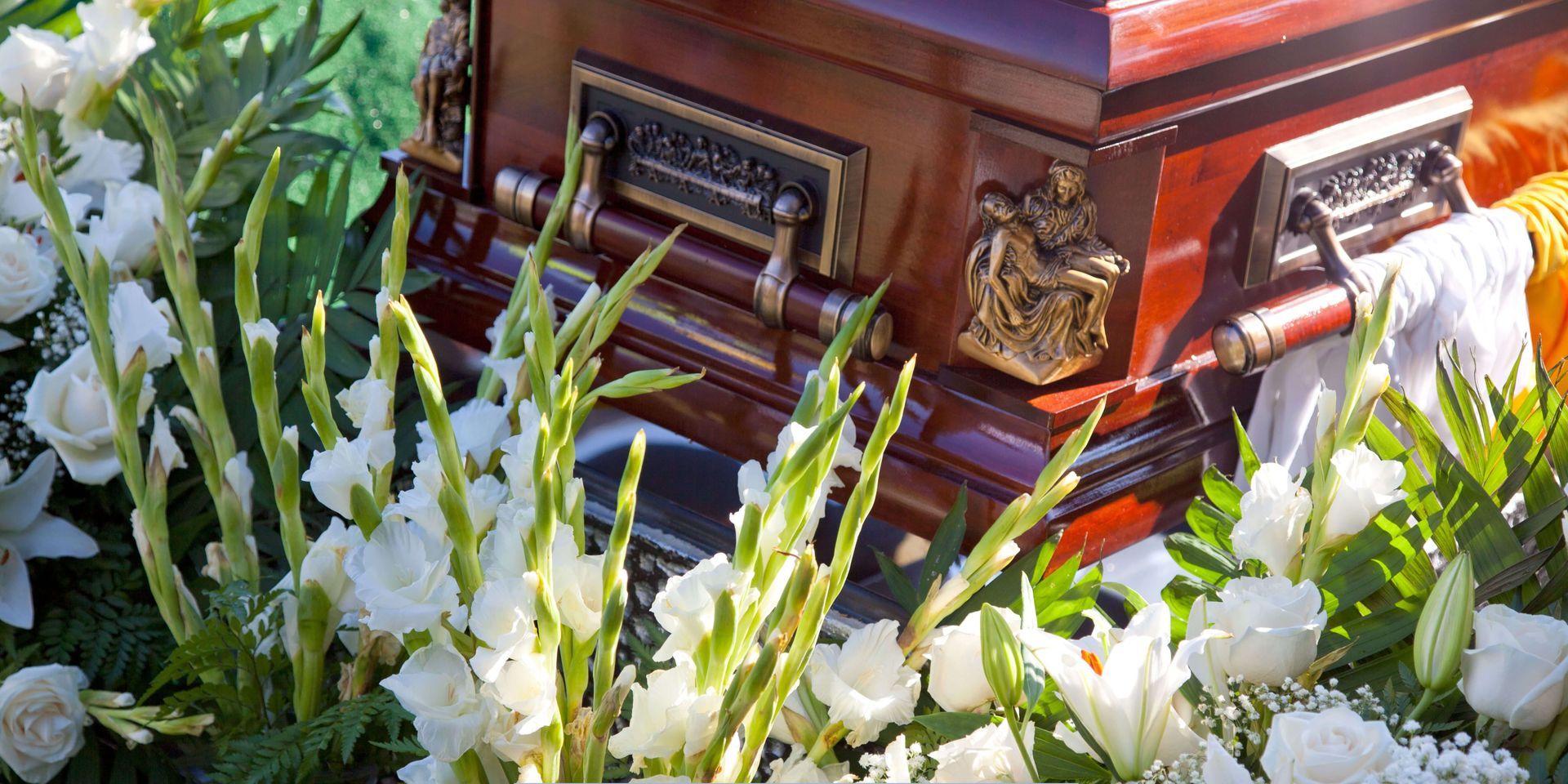 Funeral casket with floral arrangements during a memorial service, symbolizing professional funeral home and cremation services.