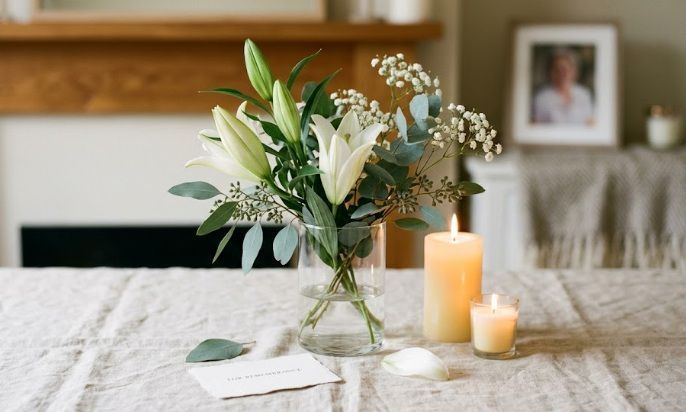 White lilies and candles arranged beside memorial photo at funeral home in Winooski, VT