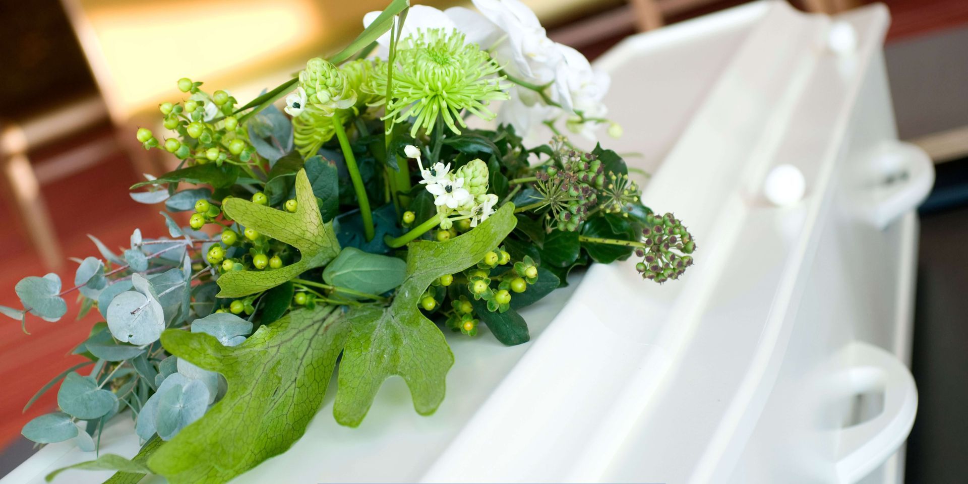 White casket adorned with a floral arrangement at a funeral service, representing dignity, remembrance, and compassionate funeral home care.