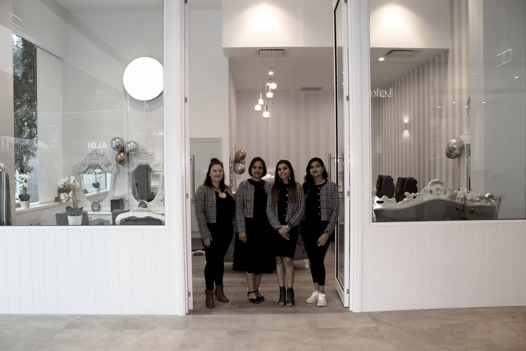 A group of women are standing in front of a hair salon.
