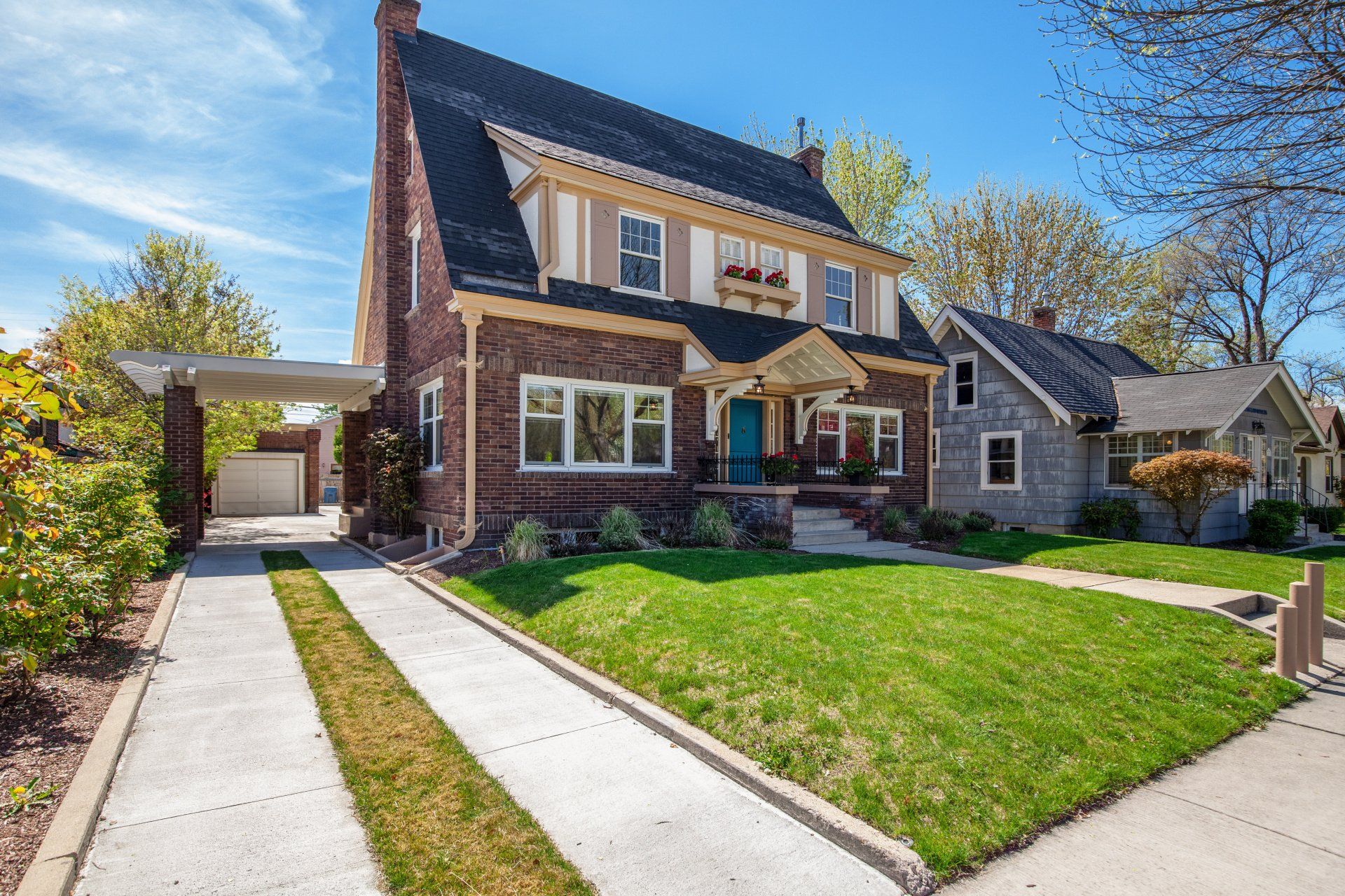A large brick house with a lush green lawn and a driveway leading to it.