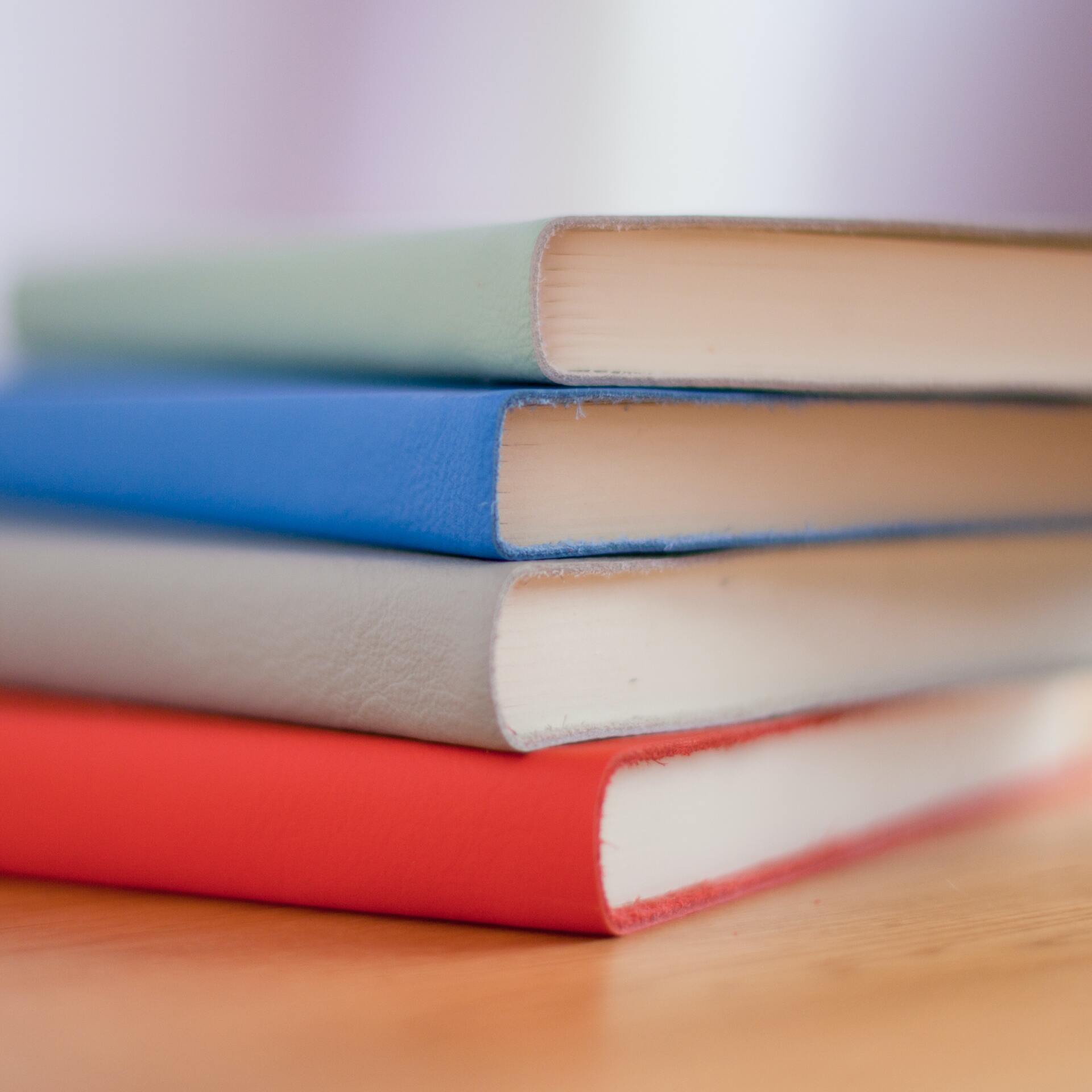 A stack of books sitting on top of each other on a wooden table.
