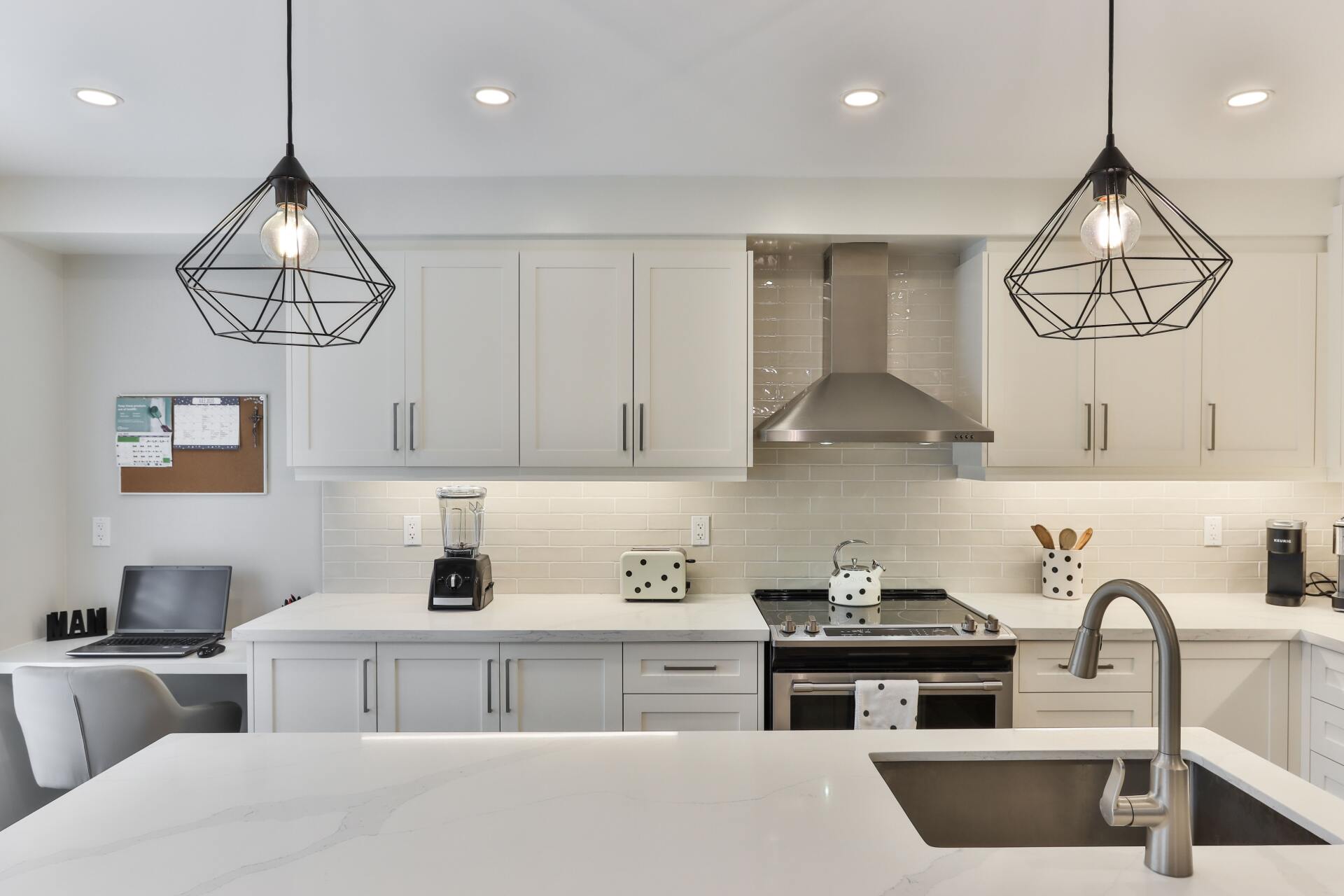 A kitchen with white cabinets , stainless steel appliances , a sink and a stove.