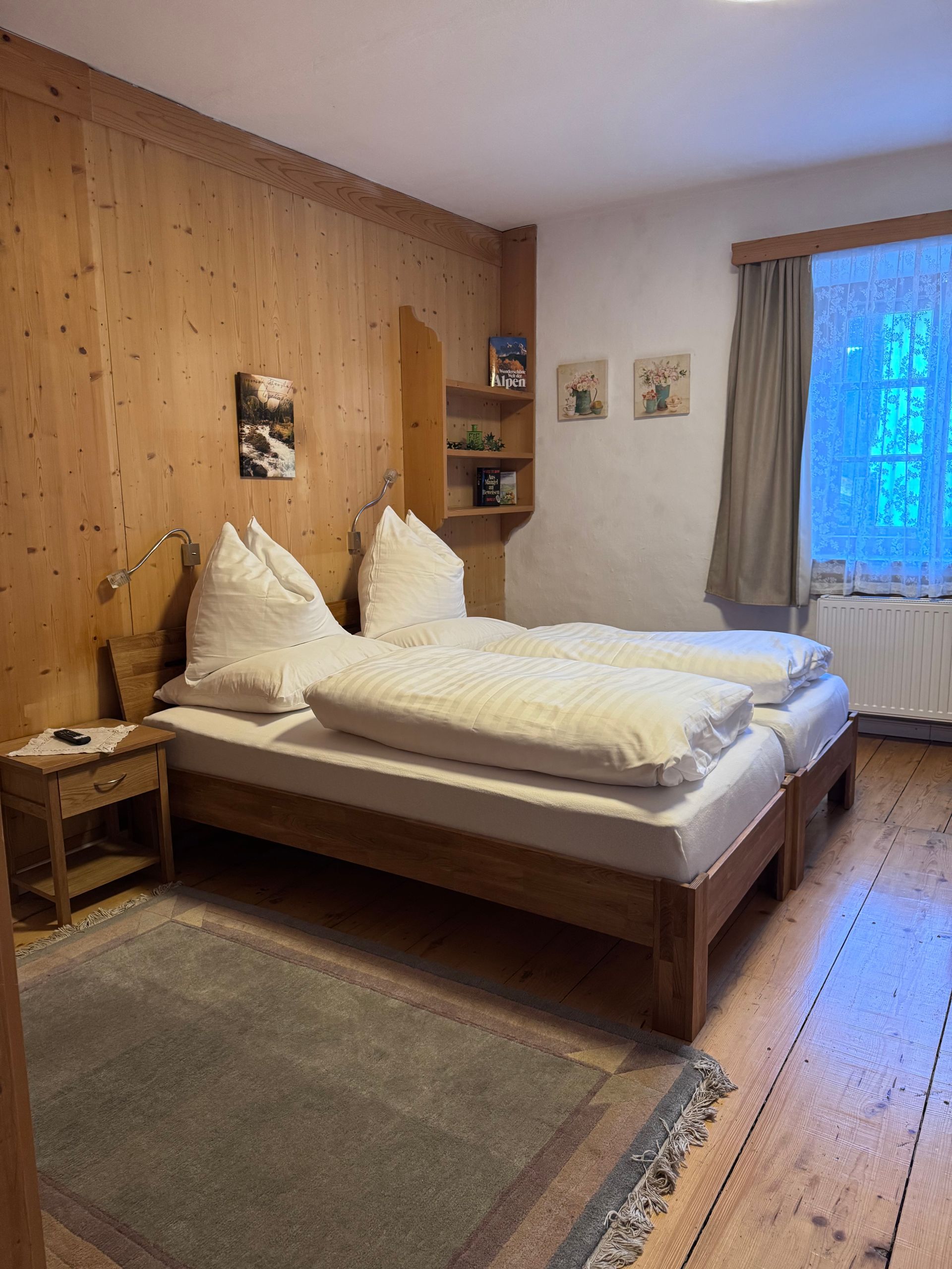 Ein Schlafzimmer mit zwei Betten, einem Nachttisch und einem Fenster.
