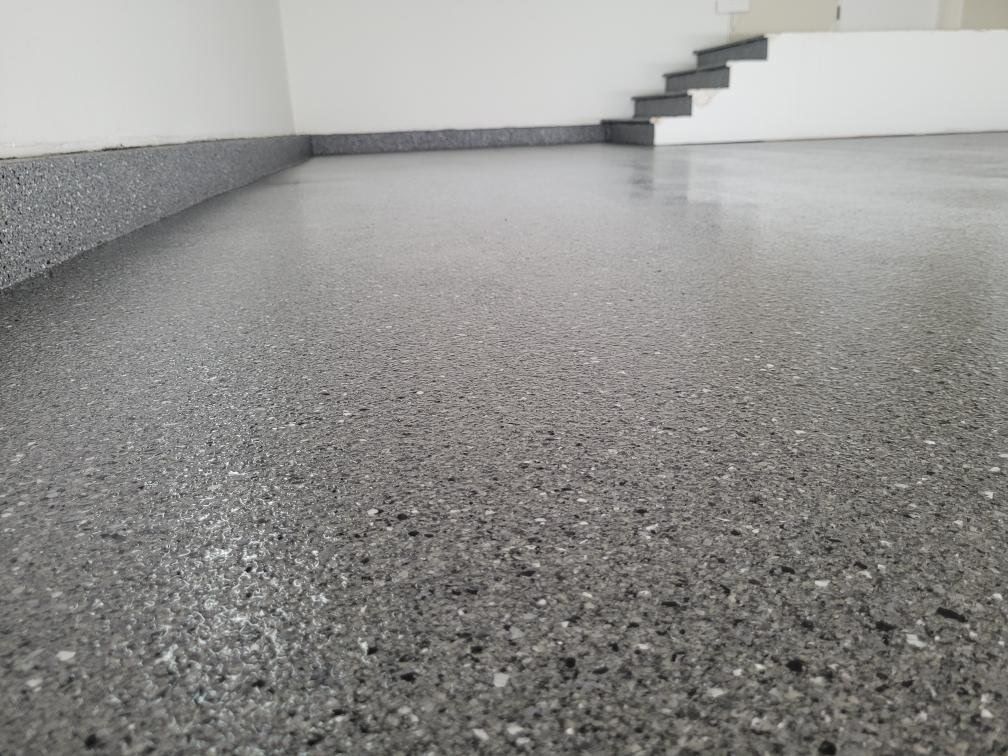 A close up of a gray concrete floor with stairs in the background.