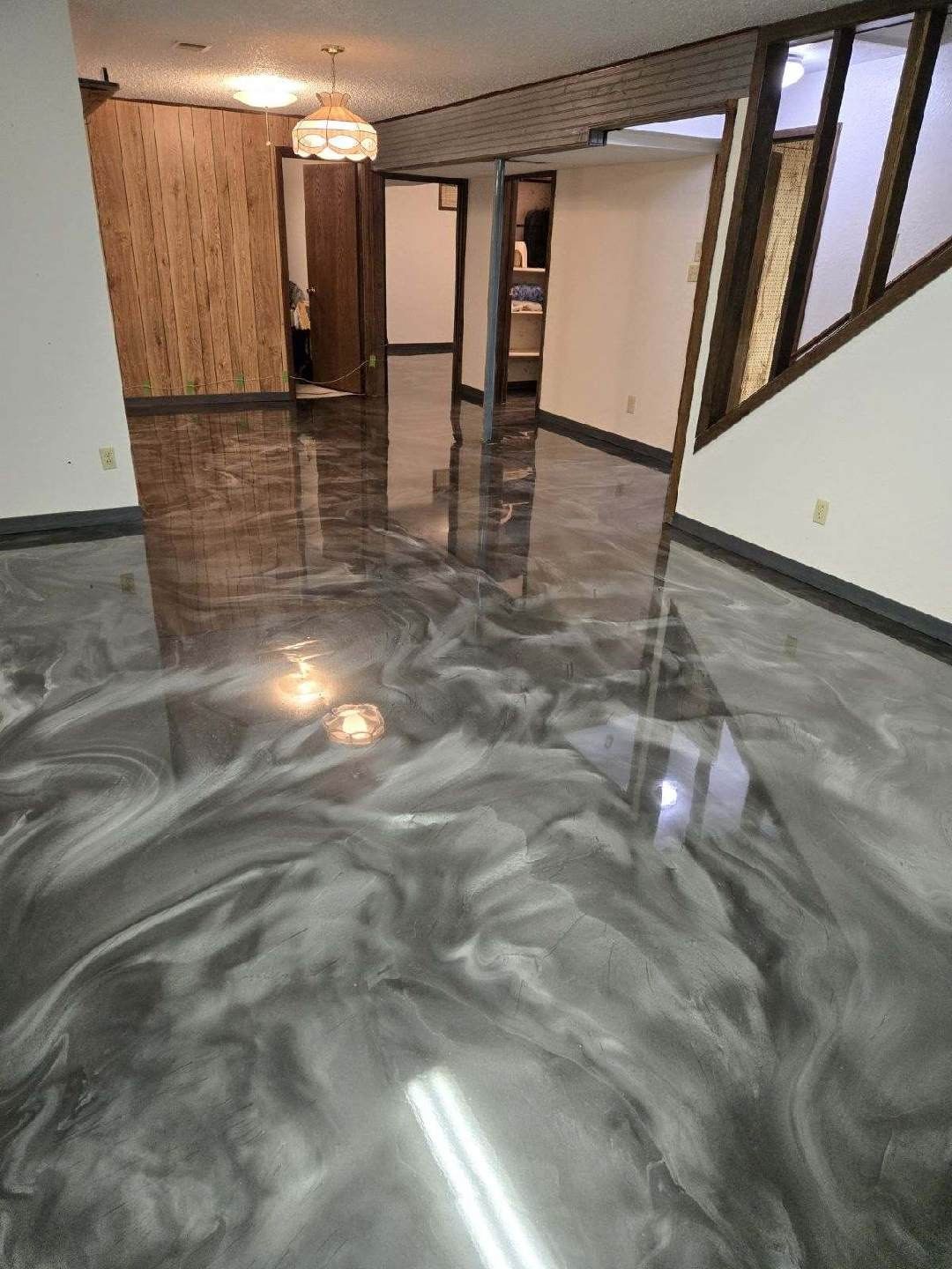 A living room with a shiny metallic floor and a staircase.