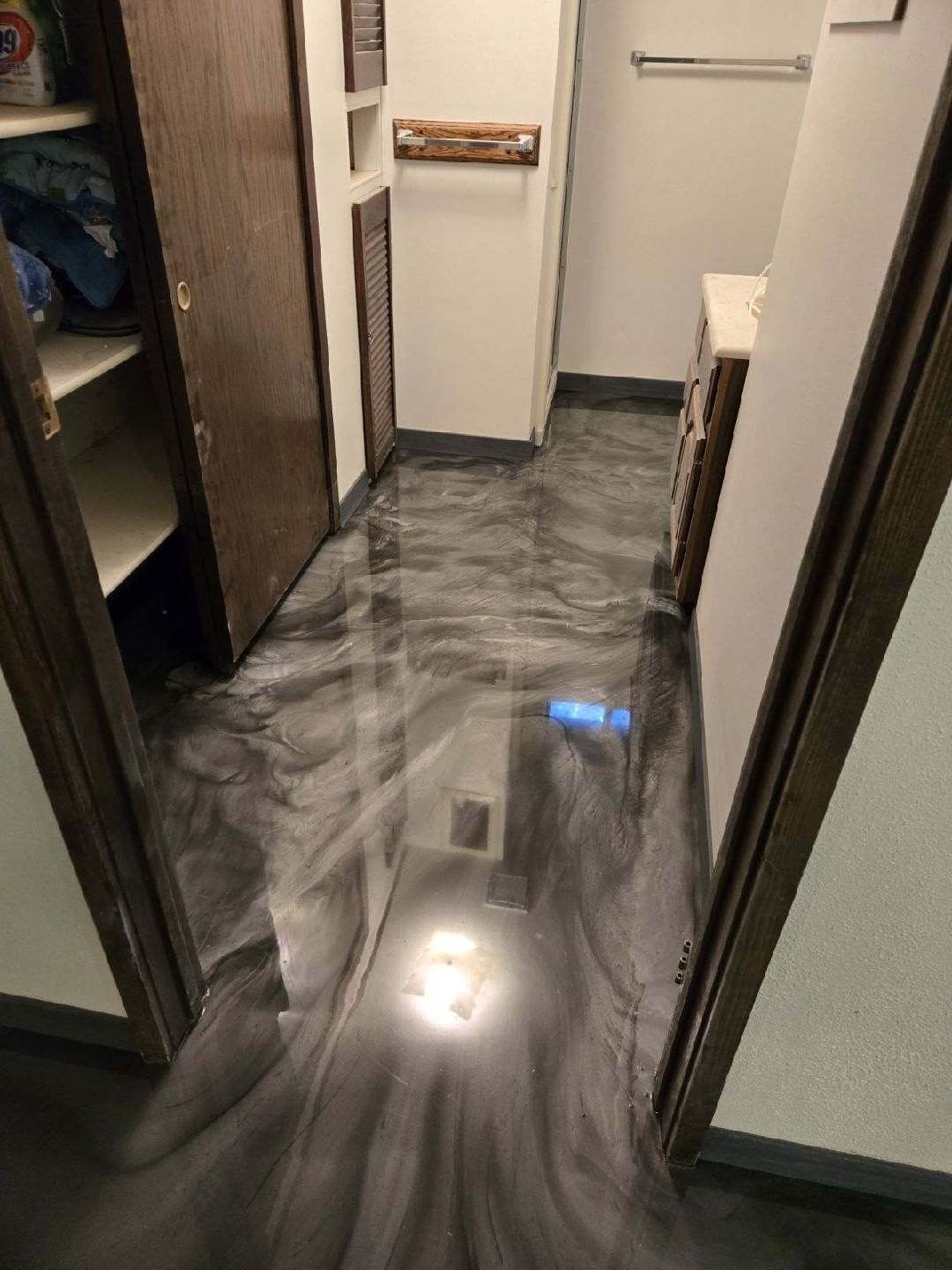A hallway with a metallic floor in a bathroom.
