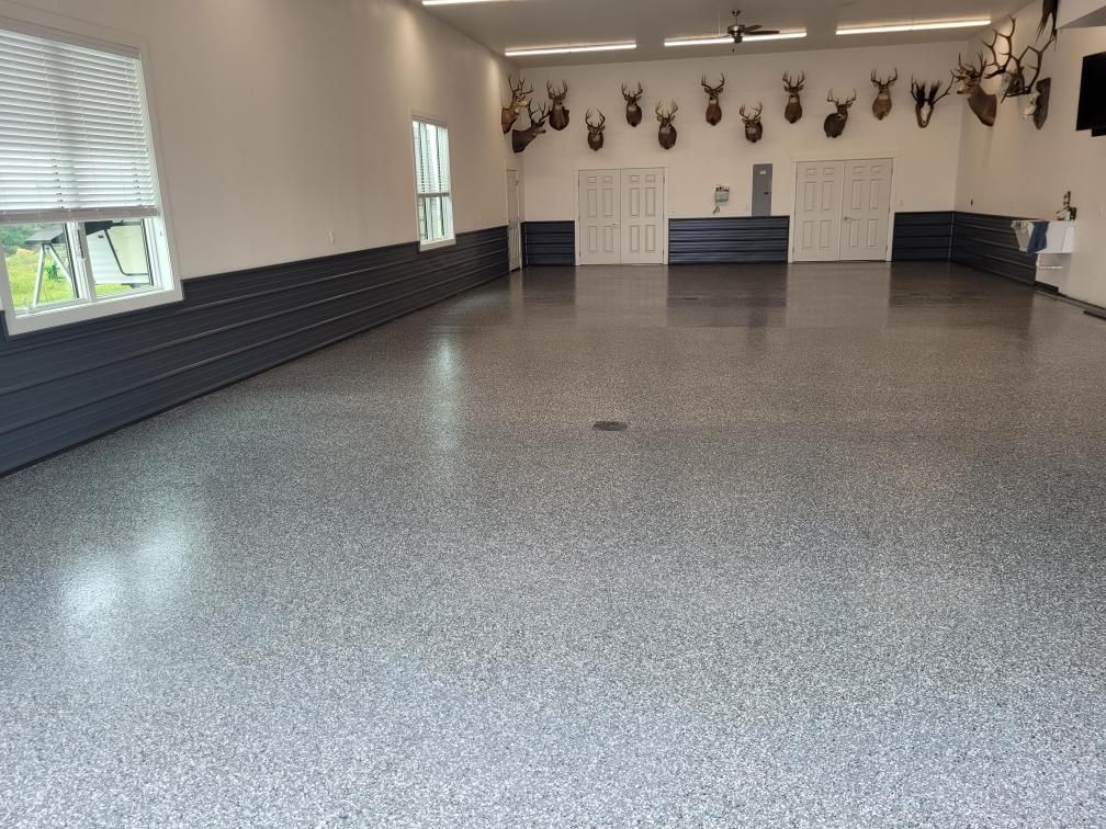 A large room with a gray floor and deer heads on the wall.